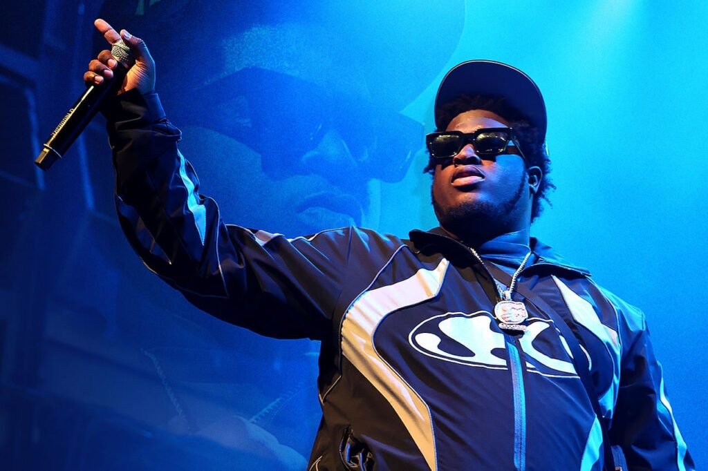 Cash Cobain performing live, bathed in neon light, representing his slizzy music style of sensual beats and raw energy
