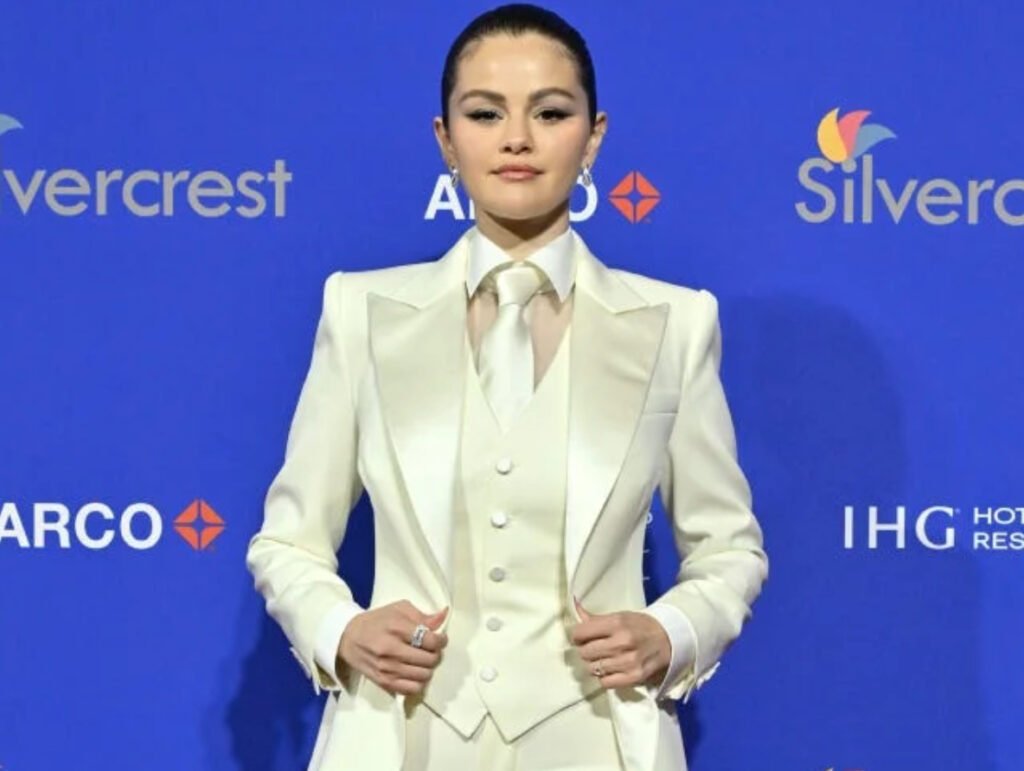 Selena Gomez poses in a tailored white tuxedo with satin lapels, paired with pointed heels and soft waves, redefining bridal style