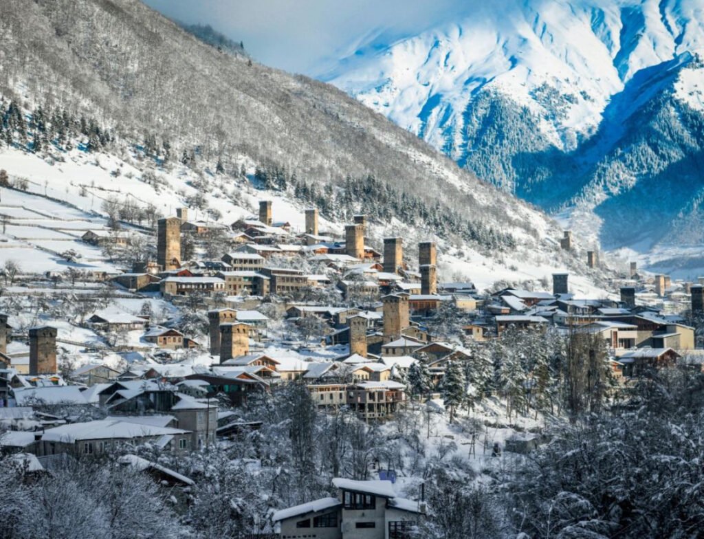 A breathtaking view of Mestia’s snow-covered slopes in Georgia’s Caucasus Mountains, with medieval Svan towers in the background
