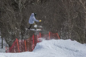 A skier mid-air performing a trick at Real To Steel 2025 at Jay Peak Resort, showcasing freeride and slopestyle skills