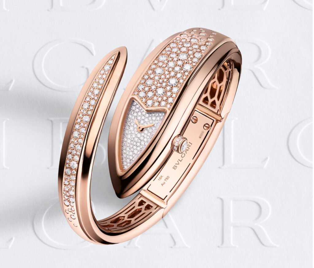 Close-up of a BVLGARI Serpenti bracelet in rose gold with diamond accents, coiled around the wrist against a silk backdrop