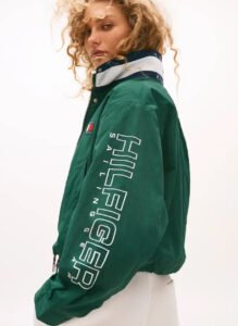 Tommy Hilfiger model wearing color-block sailing jacket and nautical pants from 2025 capsule, standing on yacht deck