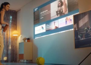 Samsung Ballie robot assistant rolling on hardwood floor, projecting media onto nearby wall