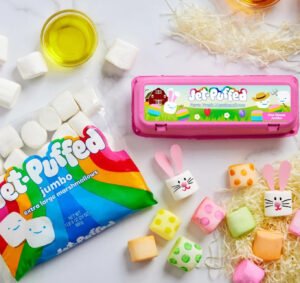 Jet-Puffed DIY Marshmallow Easter Kit with colorful icing, candy decorations, and egg-shaped marshmallows on a spring-themed table