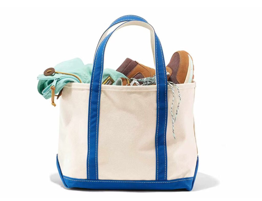 L.L.Bean Boat ‘n Tote bag in natural canvas with navy handles, placed on a picnic blanket