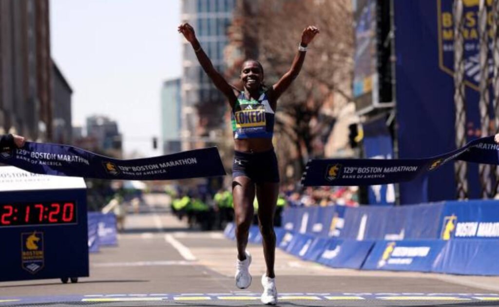 Sharon Lokedi crossing the Boston Marathon finish line with arms raised after setting a new course record