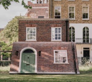 Visitors walking beneath Alex Chinneck’s arched brick facade sculpture at Clerkenwell Design Week 2025 in London
