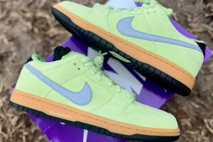 Nike SB Dunk Low ‘Verdugo Mountain’ shoe featuring olive green suede overlays, tan leather panels, and a moss green Swoosh, displayed against a scenic outdoor-inspired background
