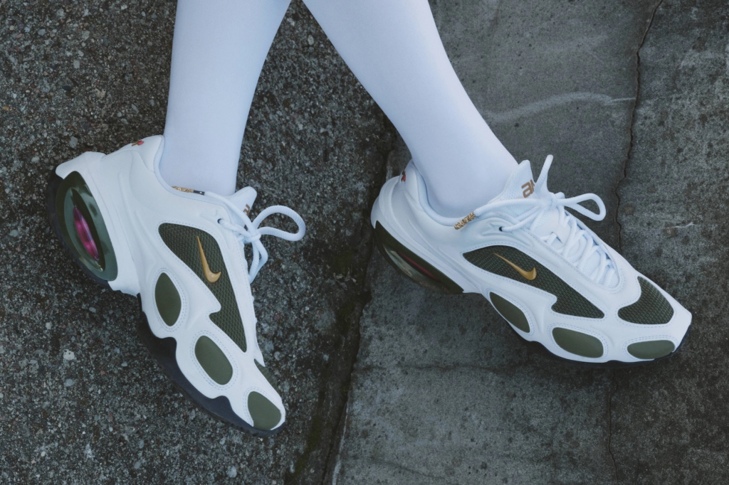 Veneda Carter x Nike Air Max Muse shoe, white and olive green design with gold accents, worn with white tights on concrete