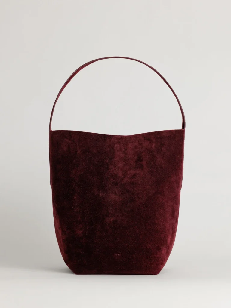 Front view of the Teresa Tote in deep burgundy suede, featuring a minimalist bucket silhouette with a bonded strap and soft texture.
