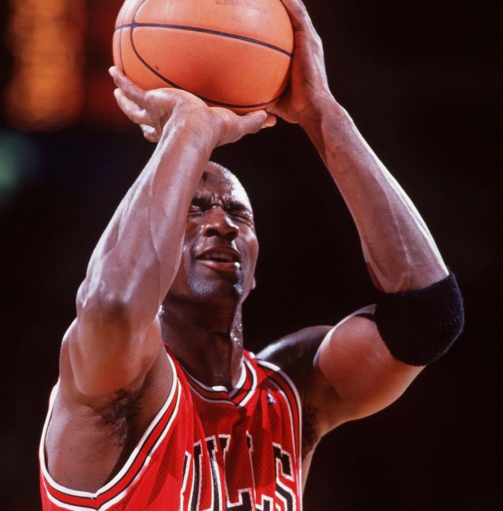 Michael Jordan in a Chicago Bulls jersey taking a free throw with his eyes closed during an NBA game, showcasing his legendary confidence and swagger.