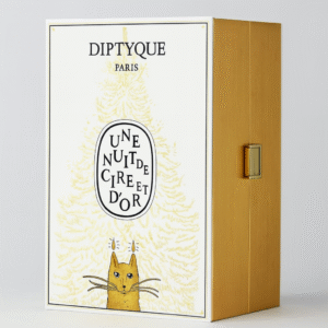 Diptyque Paris “Une Nuit de Cire et d’Or” Advent Calendar 2025 box featuring a gold and white design with an illustrated cat beneath a stylized fir tree, housed in a gold cabinet-style case with a metallic clasp.
