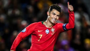 Cristiano Ronaldo smiling and giving a thumbs-up while wearing Portugal’s red national team jersey with number 7, during an international football match.