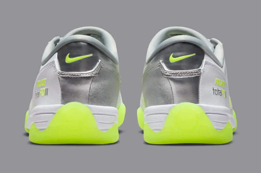 Rear view of the Palace x Nike Total 90 III sneakers showing metallic silver heel panels, Volt green Nike Swoosh logos, and embossed “Palace total 90 iii” branding above the bright neon yellow outsoles.