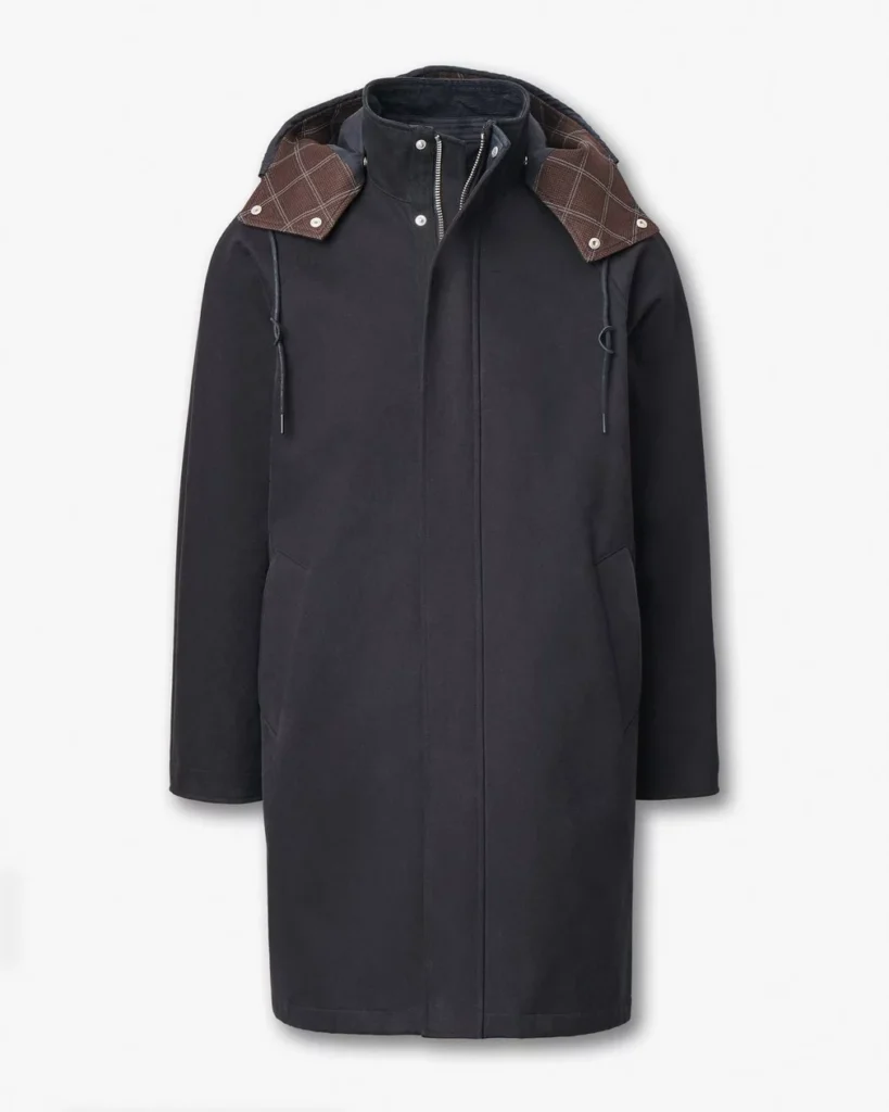 full front view of the Rag & Bone Garret Coat in matte black, featuring a mid-length silhouette with concealed zip closure, angled pockets, and a detachable hood lined in brown plaid fabric for a refined urban look