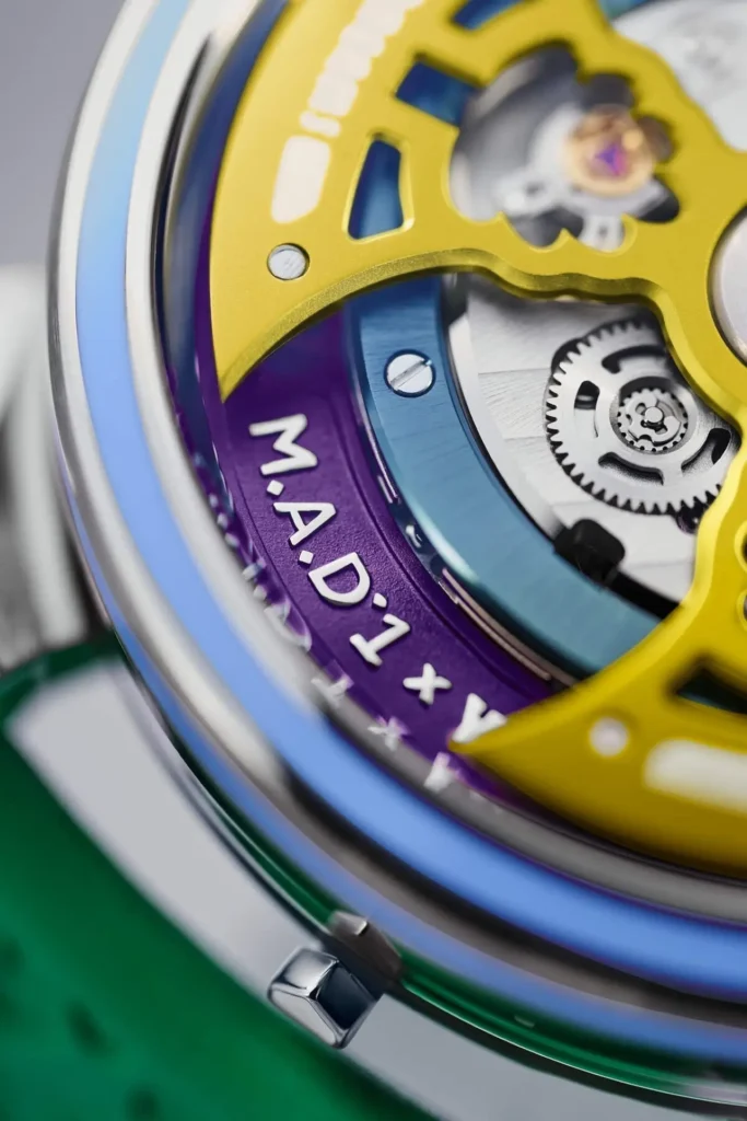 Extreme close-up of the Yinka Ilori × M.A.D. Editions × MB&F watch movement, highlighting the yellow rotor bridge, purple ring engraved with “M.A.D.1 × YINKA ILORI,” and visible gears beneath. The image showcases the vivid color layering and intricate mechanical detailing characteristic of the collaboration