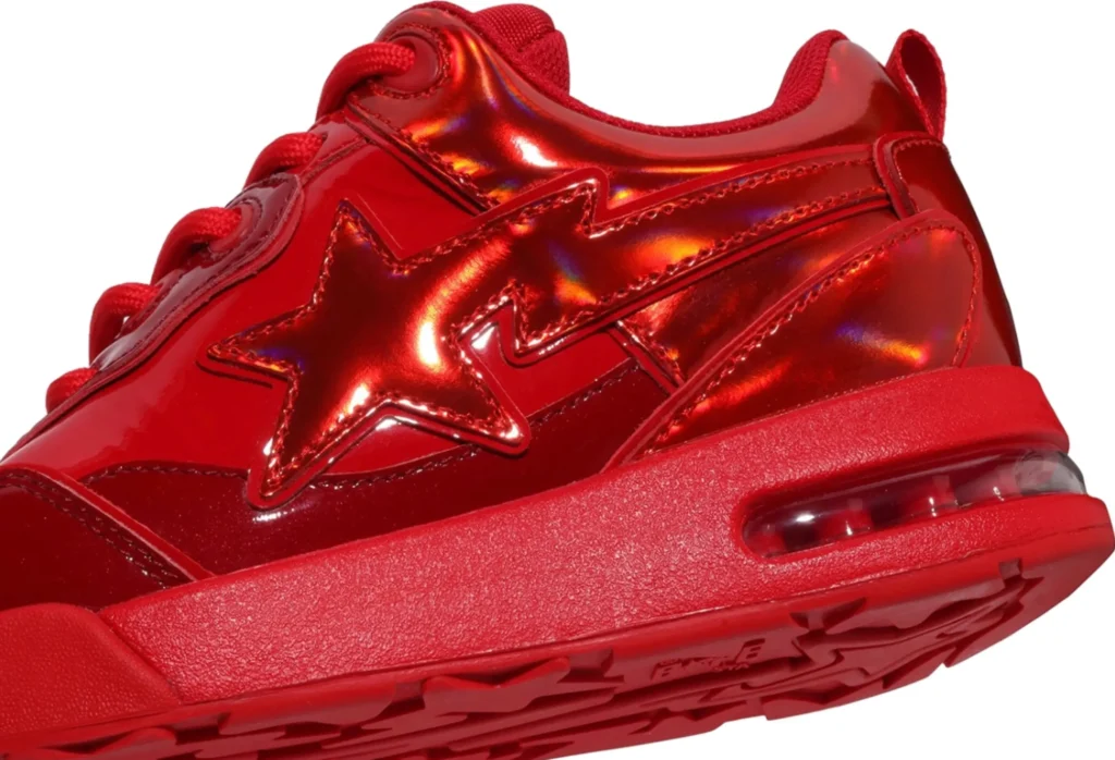A side profile of the Bape US Limited Flip Sta Red sneaker showing the flipped red star logo, glossy red leather overlays, and smooth white underlays. The shoe is angled slightly upward, revealing the red outsole and crisp white midsole