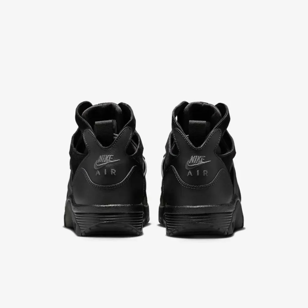 Rear view of the Nike Air Trainer Huarache “Triple Black” sneakers, featuring the embossed Nike Air logo on the heel panel, cut-out ankle design, and sculpted black midsole, emphasizing the shoe’s stealth aesthetic and supportive structure