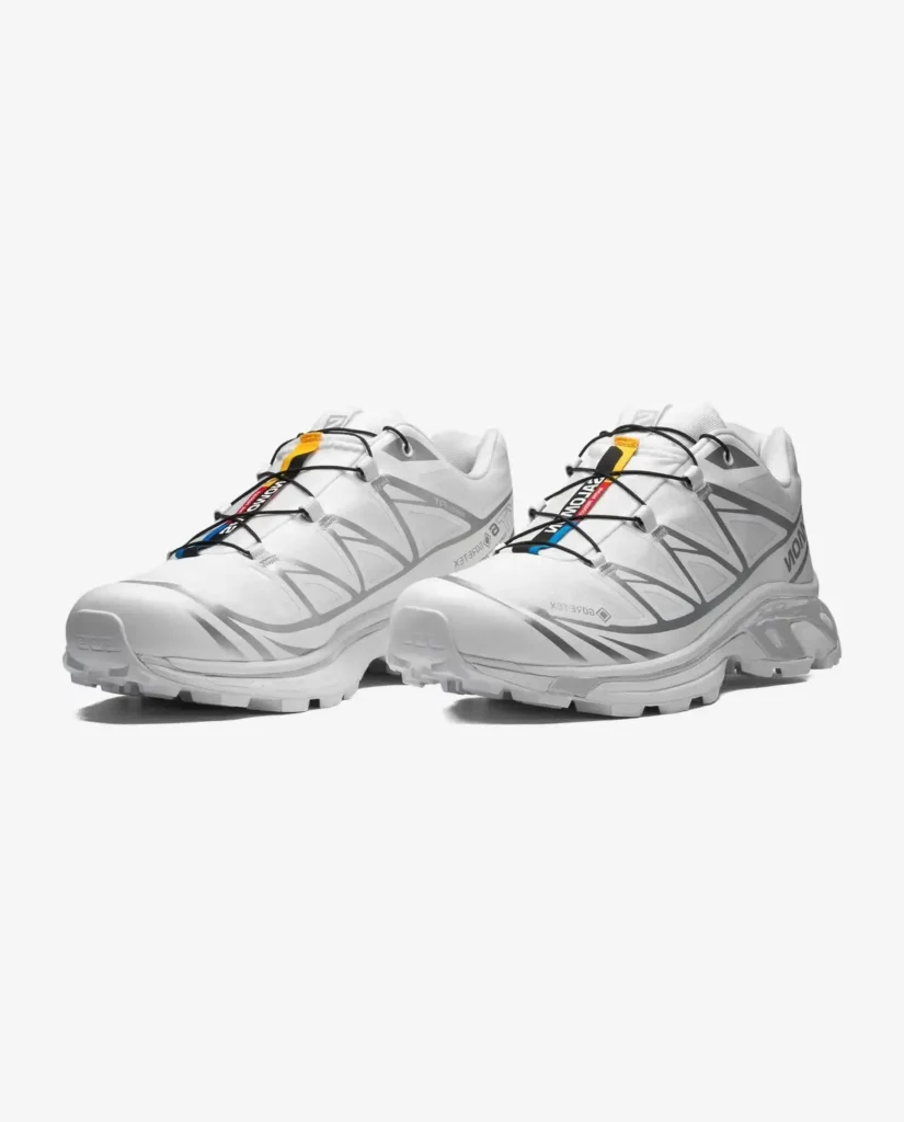 Salomon XT-6 GORE-TEX shoe pair in off-white and beige tones, photographed on a neutral surface to emphasize its waterproof membrane, durable mesh panels, and trail-inspired silhouette adapted for city wear.