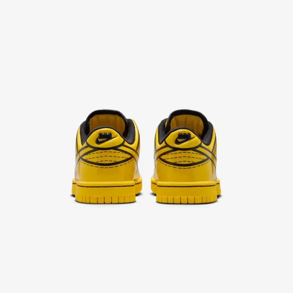Rear view of the LEGO x Kids Nike Dunk Low “Tour Yellow,” showing the bright yellow glossy heel panels with bold black cartoon-style outlines, black Nike heel logos, and matching yellow midsoles and outsoles. Both shoes sit side-by-side against a plain white background