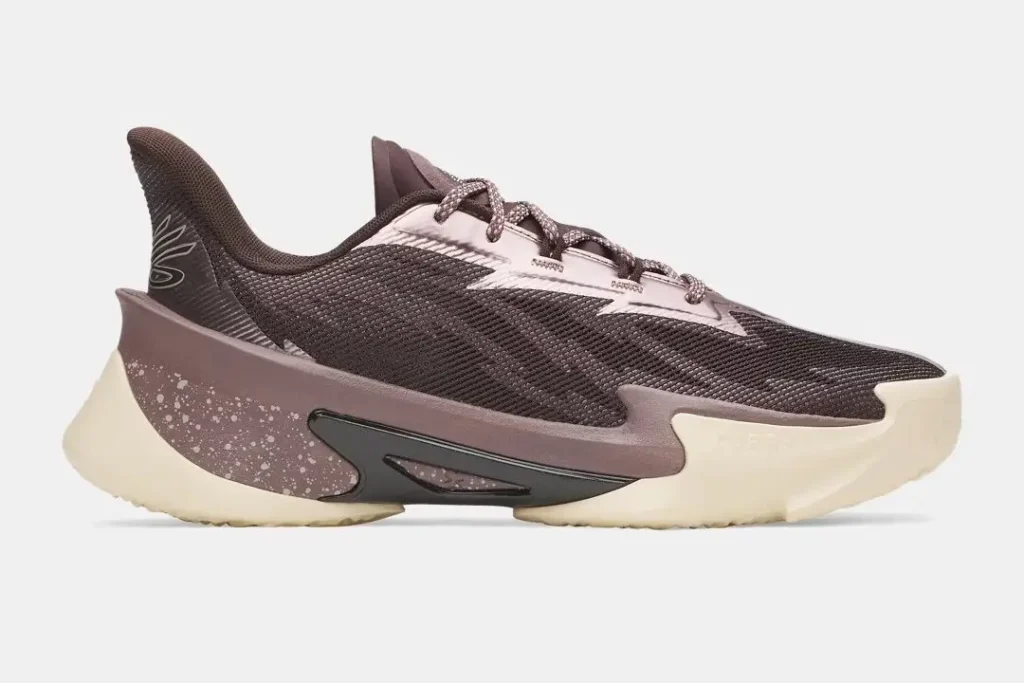 A side profile of the Under Armour Curry 7 “Craft” basketball shoe in a muted brown and mauve colorway, featuring a textured mesh upper, speckled midsole detailing, sculpted heel support, and a cream rubber outsole