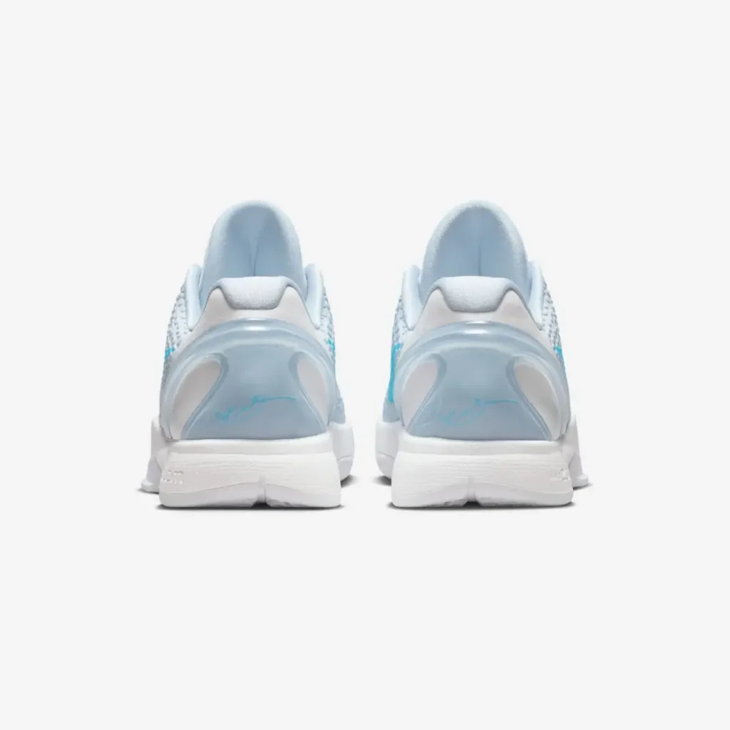 A rear view of the Nike Kobe 6 Protro “Caitlin Clark,” showing the twin icy blue TPU heel counters with Caitlin Clark’s signature stamped in bright blue. The padded light-blue collars sit above a white midsole and outsole, emphasizing the shoe’s sculpted heel shape and balanced low-profile design