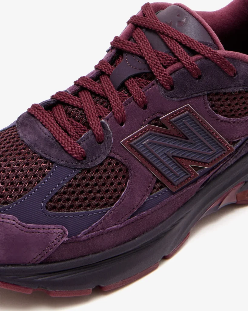 Close-up of the Rich Paul x New Balance 2010 sneaker in plum-brown suede and burgundy mesh, highlighting the textured “N” logo, tonal rope laces, and layered ABZORB midsole for a refined, luxury running-inspired look