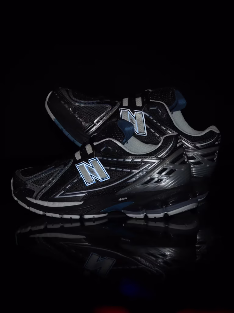 pair of the New Balance 1906R “Blue Moon” shoes by atmos, showcasing its deep navy mesh upper, metallic silver heel counter, and layered blue gradient accents, photographed against a soft grey background that highlights the shoe’s lunar-inspired details