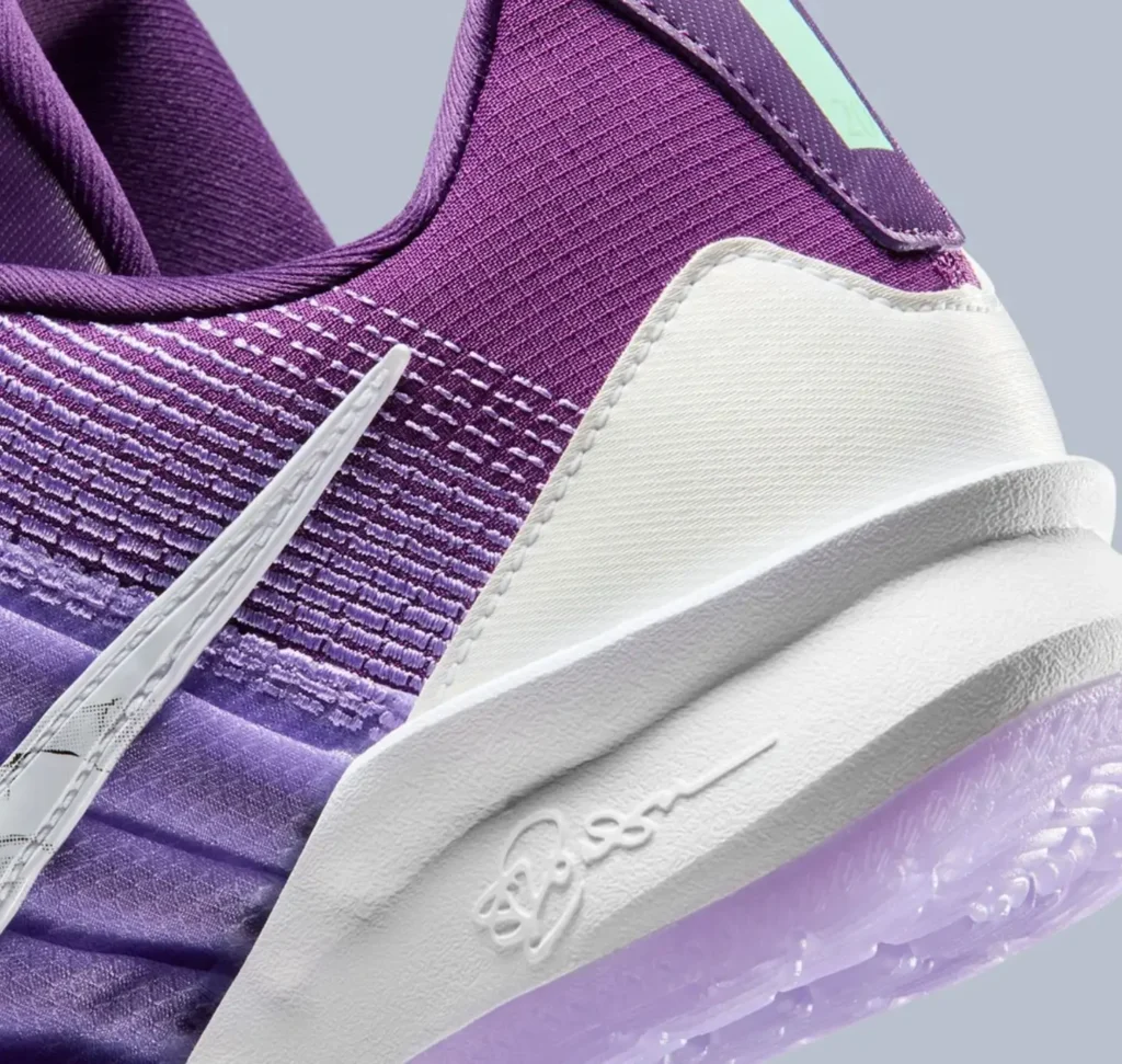 Close-up of the Nike Sabrina 3 “Flowers” heel showing the gradient purple knit upper, white heel counter, Sabrina Ionescu’s embossed signature on the midsole, and the marbled floral-patterned silver Swoosh against a soft grey background