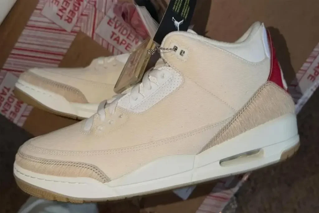 Leaked Levi’s x Air Jordan 3 ‘Sail’ sneaker featuring a cream denim upper, frayed-texture overlays, white laces, off-white midsole, and red heel panel, photographed indoors with shipping boxes in the background