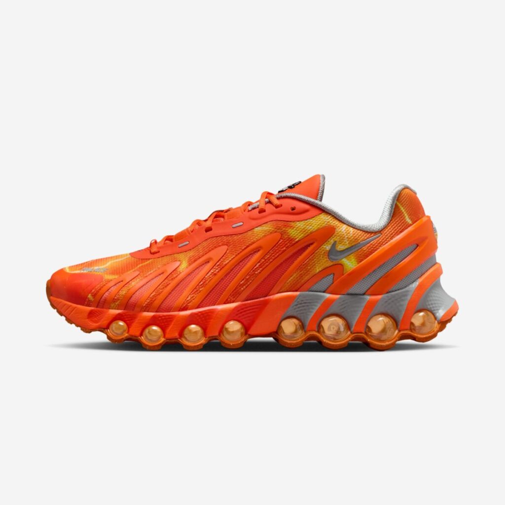 Side profile of the Palace x Nike Air Max DN8 “Safety Orange” sneaker, featuring a high-visibility orange mesh upper with flowing molded overlays, metallic silver Swoosh, grey heel panel, and a sculpted DN8 sole with multiple visible Air chambers on a white background