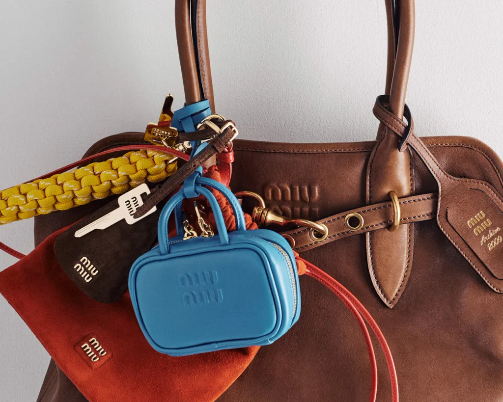 Close-up of a Miu Miu bag showcasing layered accessories, key charms, and leather mini cases in rich contrasting tones