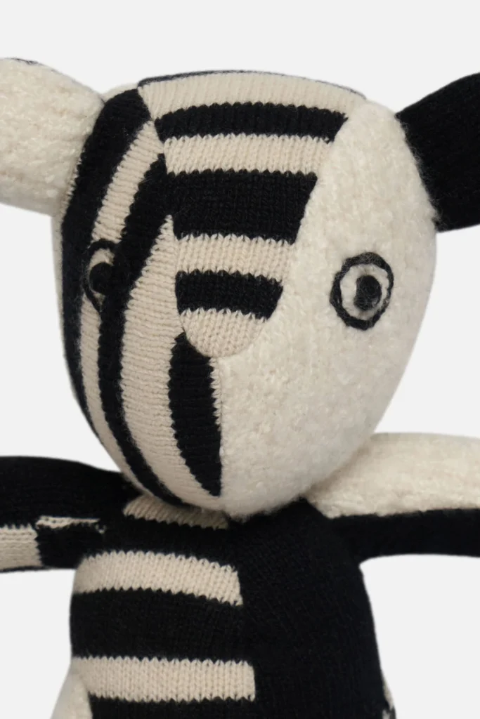 Close-up of The Elder Statesman Cashmere Teddy’s face, showing black-and-ivory striped knit detailing, hand-stitched eyes, and soft textured cashmere fabric