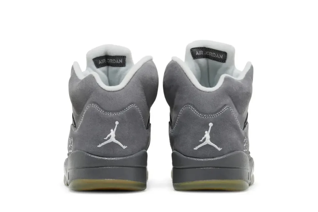 Rear view of the Air Jordan 5 “Wolf Grey” sneakers, showing grey suede heels with embroidered white Jumpman logos, padded ankle collars, and subtle contrast between the upper and midsole