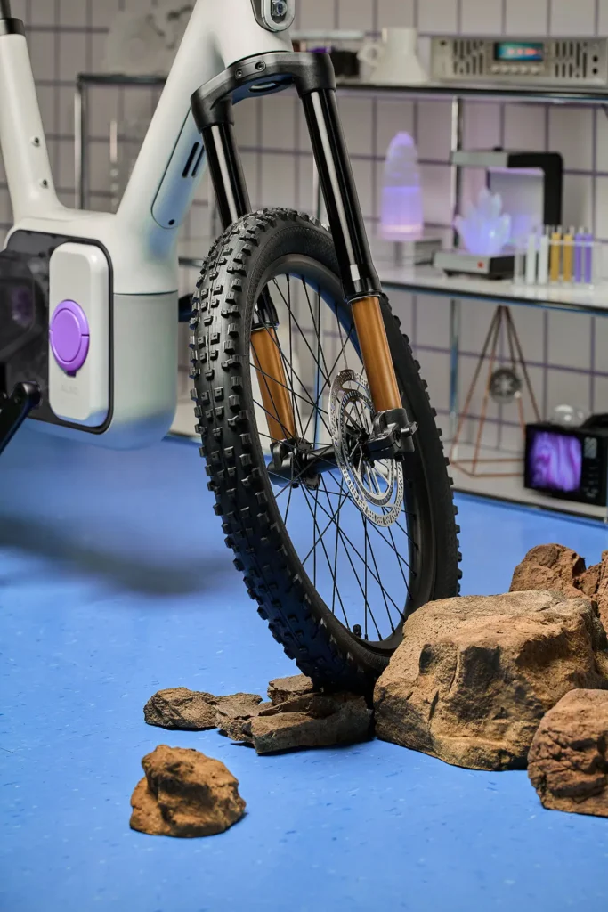 Front wheel of the ALSO TM-B electric bike shown navigating a rocky test surface, highlighting the suspension fork, hydraulic disc brake, and knobby all-terrain tire designed for stability, control, and EV-inspired performance