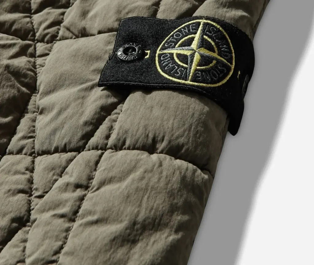 Close-up of Stone Island compass badge on Cotton Nylon Tela Quilted-TC jacket in military green