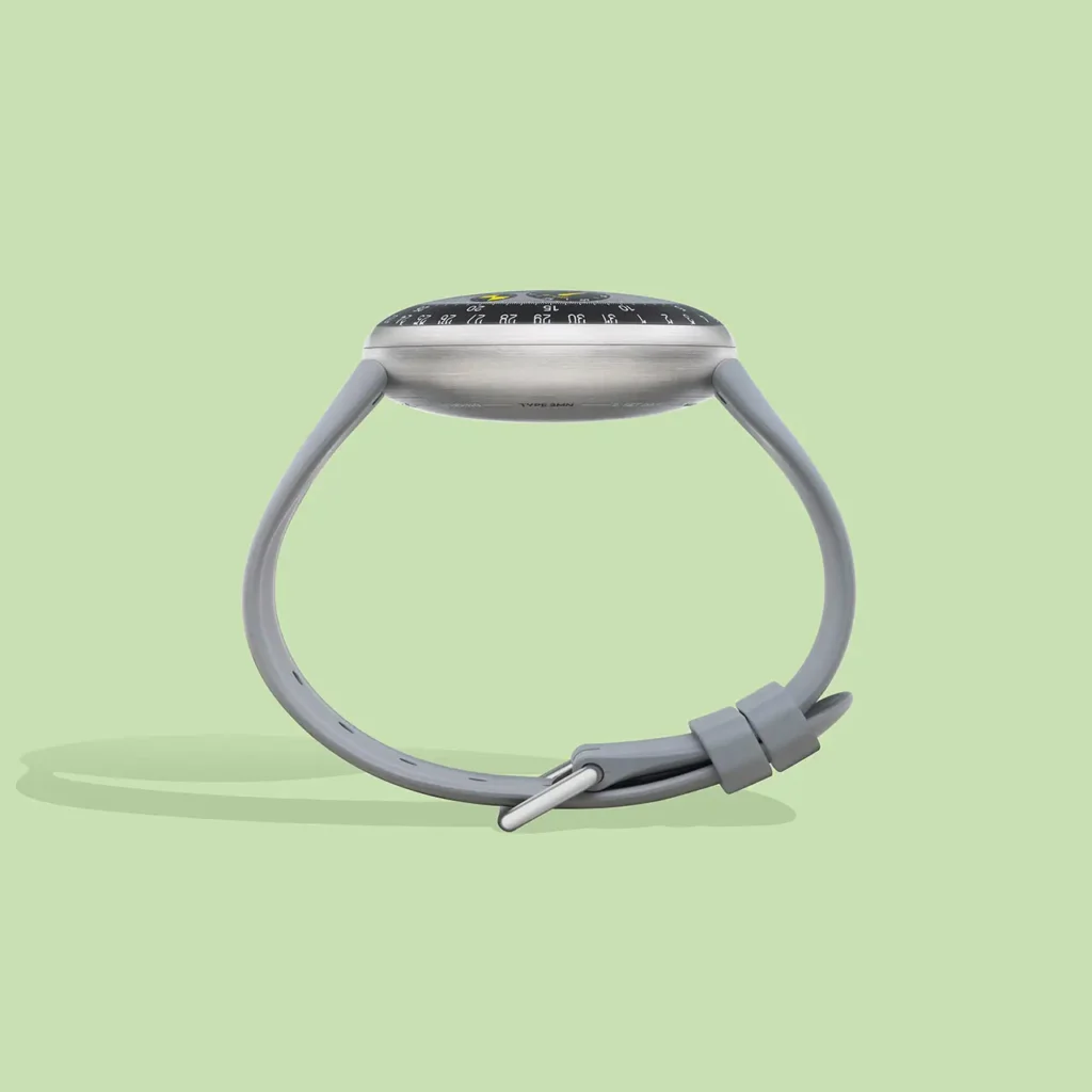 le view of the Ressence TYPE 3 MN watch by Marc Newson, highlighting the curved titanium case, domed sapphire crystal, and integrated grey rubber strap with a minimalist buckle, set against a soft pastel green background