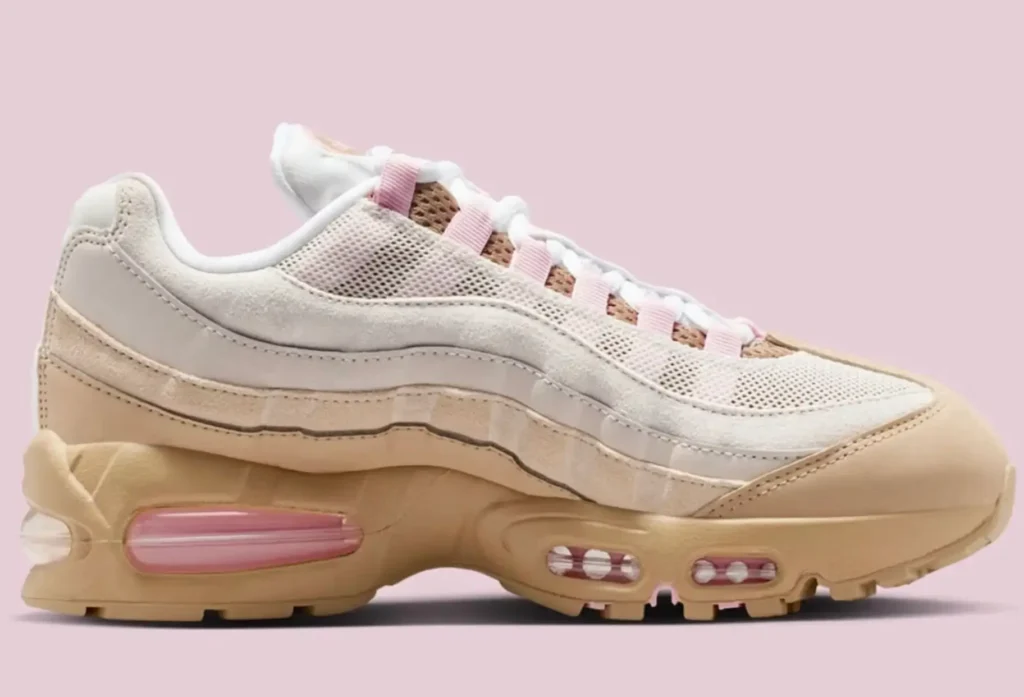 Side profile of the Nike Air Max 95 “Linen,” featuring layered cream and beige suede and mesh panels, soft pink lace loops, and a tan midsole with visible pink-tinted Air units against a pale pink background