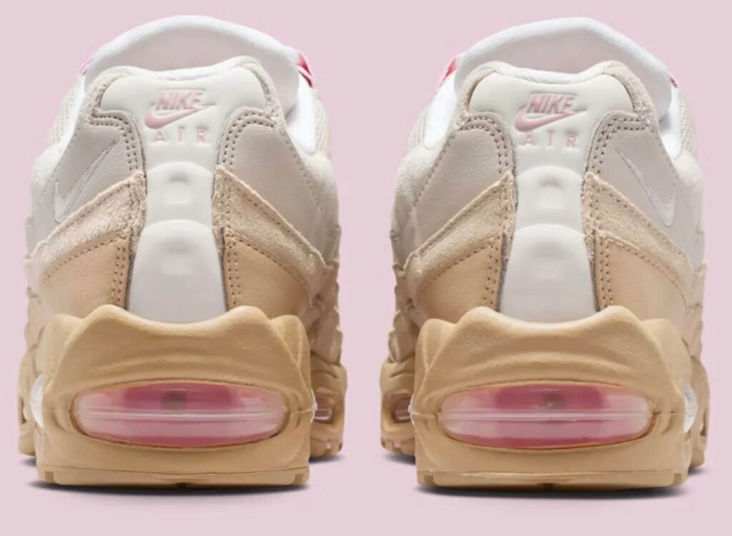 Rear view of the Nike Air Max 95 “Linen,” highlighting beige and cream layered suede panels, white heel spine, subtle pink Nike Air branding, and a tan midsole with visible pink-tinted Air cushioning units against a pale pink background