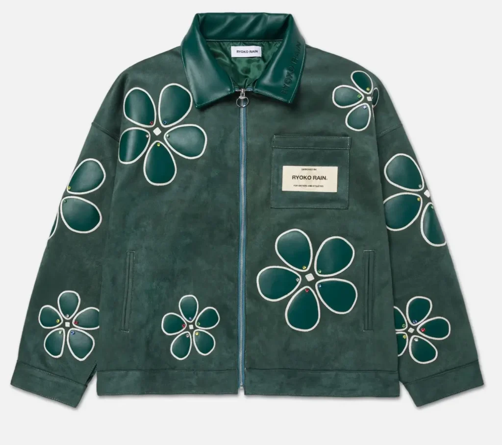 Flat-lay of a dark green suede work jacket featuring large floral appliqué motifs across the chest and sleeves, zip-front closure, glossy leather collar, front pockets, and a “Ryoko Rain” brand patch on the chest