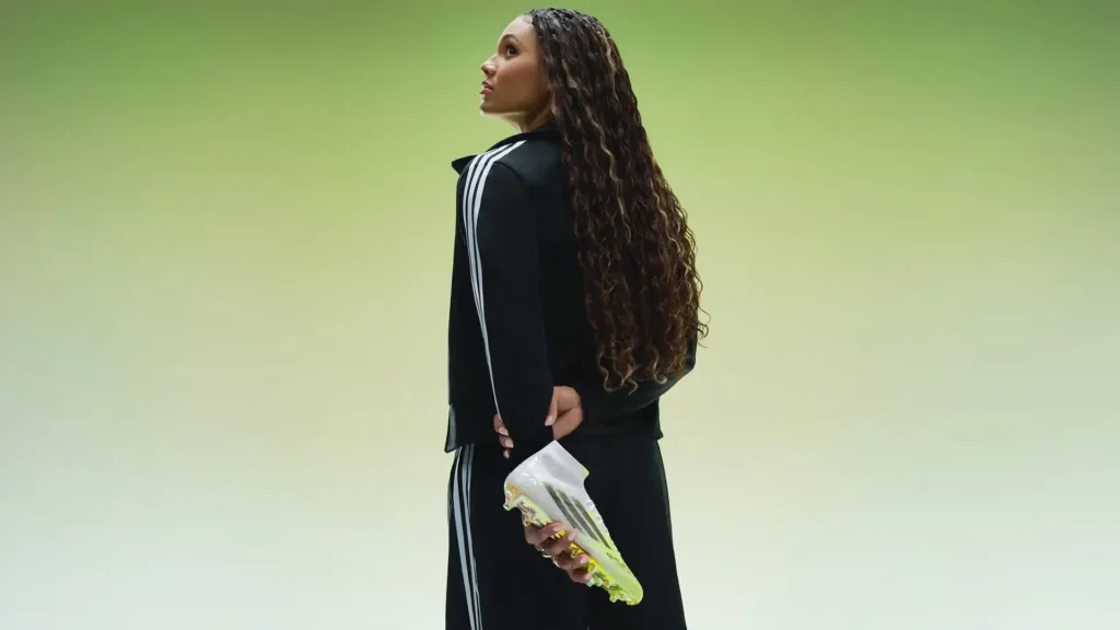 U.S. soccer star Trinity Rodman holding neon yellow adidas football boots in studio portrait