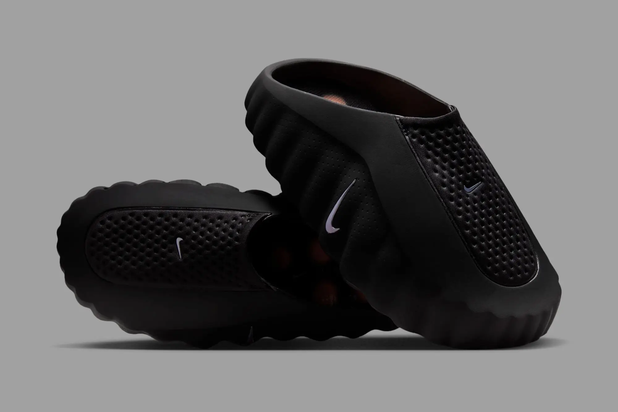Nike Mind 001 “Black” recovery sandal with sculpted foam sole and textured upper, shown in a stacked side profile on a neutral grey background
