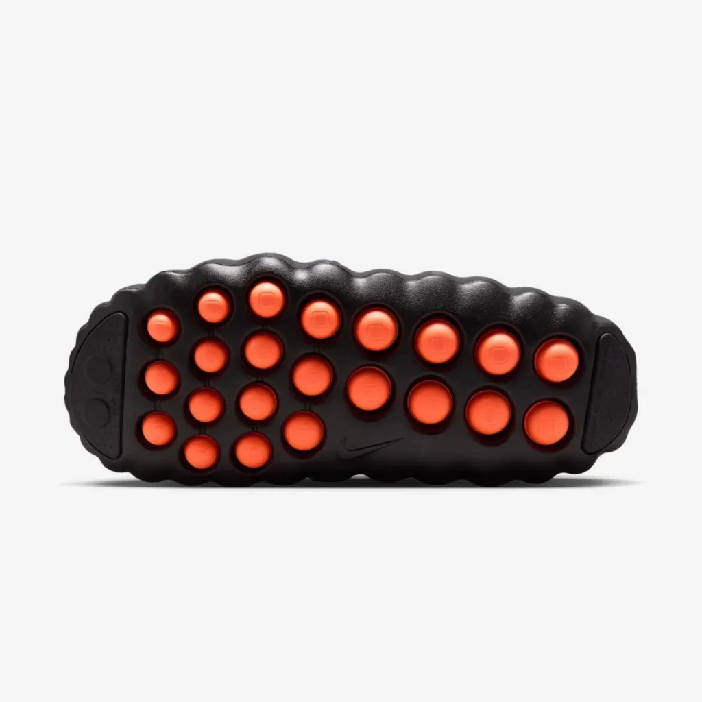 Outsole view of the Nike Mind 001 “Black” sandal featuring rounded orange traction pods set into a sculpted black foam sole