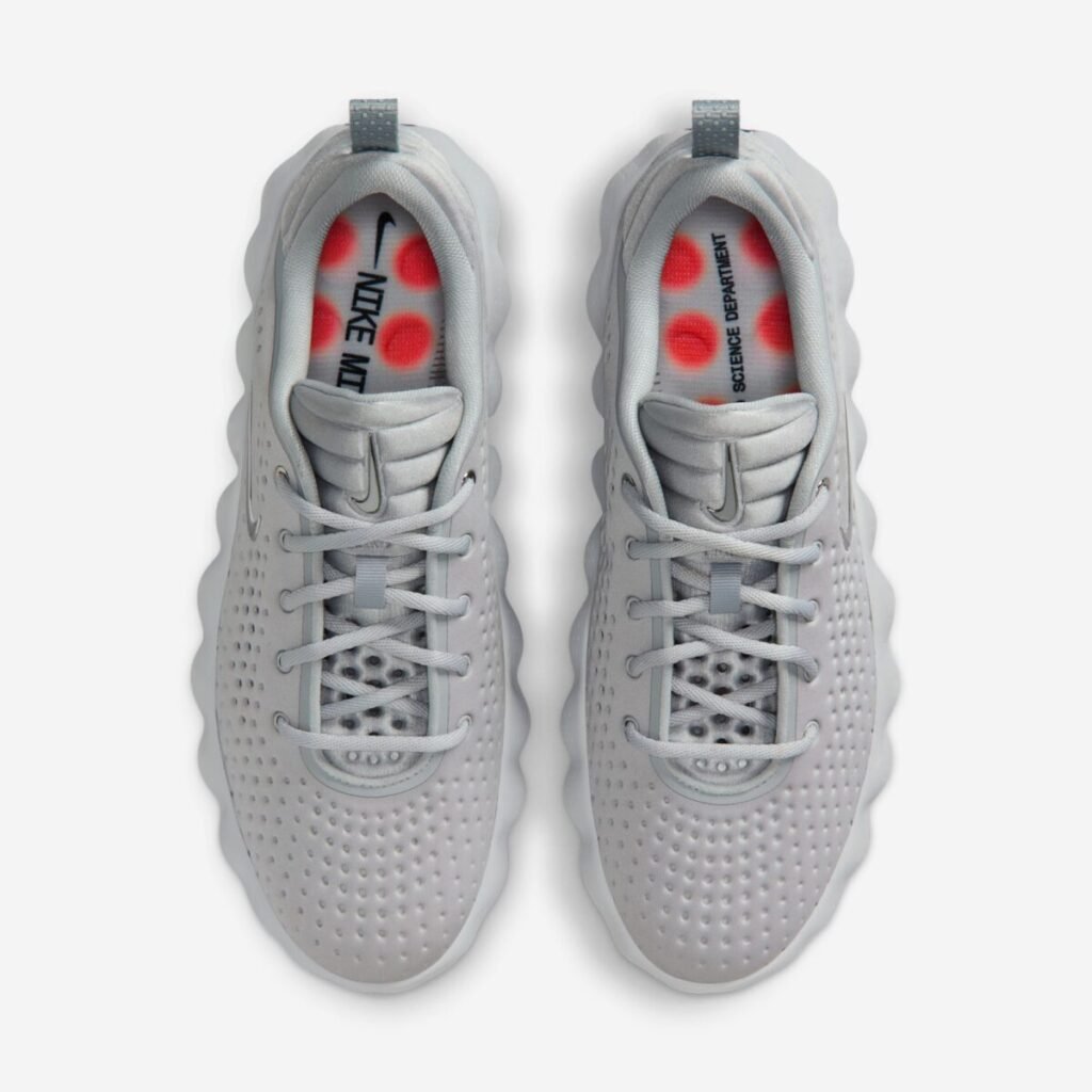 Top-down view of the Nike Mind 002 “Light Smoke Grey” sneakers, showing the perforated grey uppers, tonal laces and padded tongues, heel pull tabs, and the bright orange circular nodes visible through the translucent insole printed with “Nike Mind” and “Science Department” branding