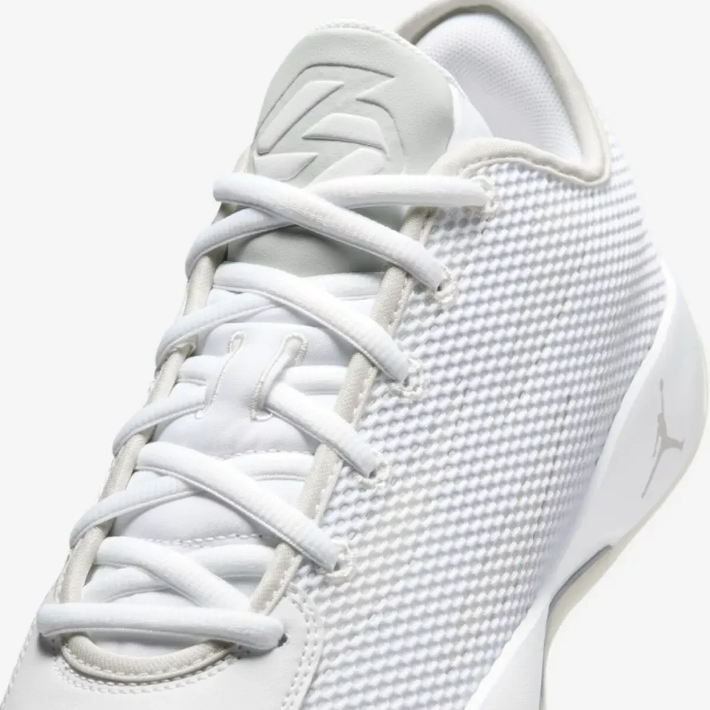 Close-up detail of the Jordan Luka .77 “Pure Money” basketball shoe, highlighting the white woven mesh upper, padded tongue with Luka Dončić logo, tonal lacing system, and smooth midsole edge in a monochrome finish