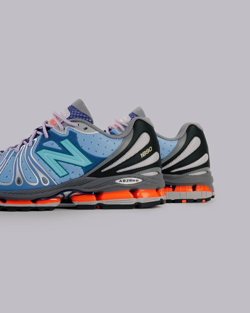 Baklava x New Balance 1890 “Cyborg Tears” sneakers in blue and grey with mint green N logo, black heel panels, orange cushioning pods, and ABZORB midsole detail on a studio grey background