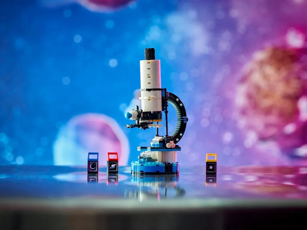LEGO Creator Space Exploration Telescope alternate microscope build displayed on a reflective surface, featuring an adjustable white-and-black microscope with gear detailing, illuminated base, and three interchangeable light tiles, photographed against a colorful, space-inspired background