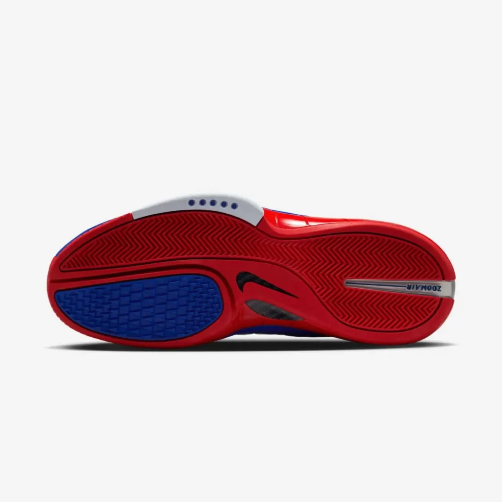 Outsole view of the Nike Air Zoom Huarache 2K4 “All-Star” sneaker featuring a red herringbone traction pattern, blue grip zones, and visible Zoom Air branding on a gray background