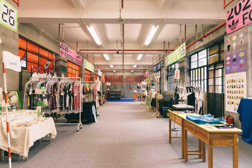 Interior view of adidas’ Shanghai flea market experience inside a converted school, featuring rows of vintage football jerseys, creative booths, and retro signage in an industrial-style hallway