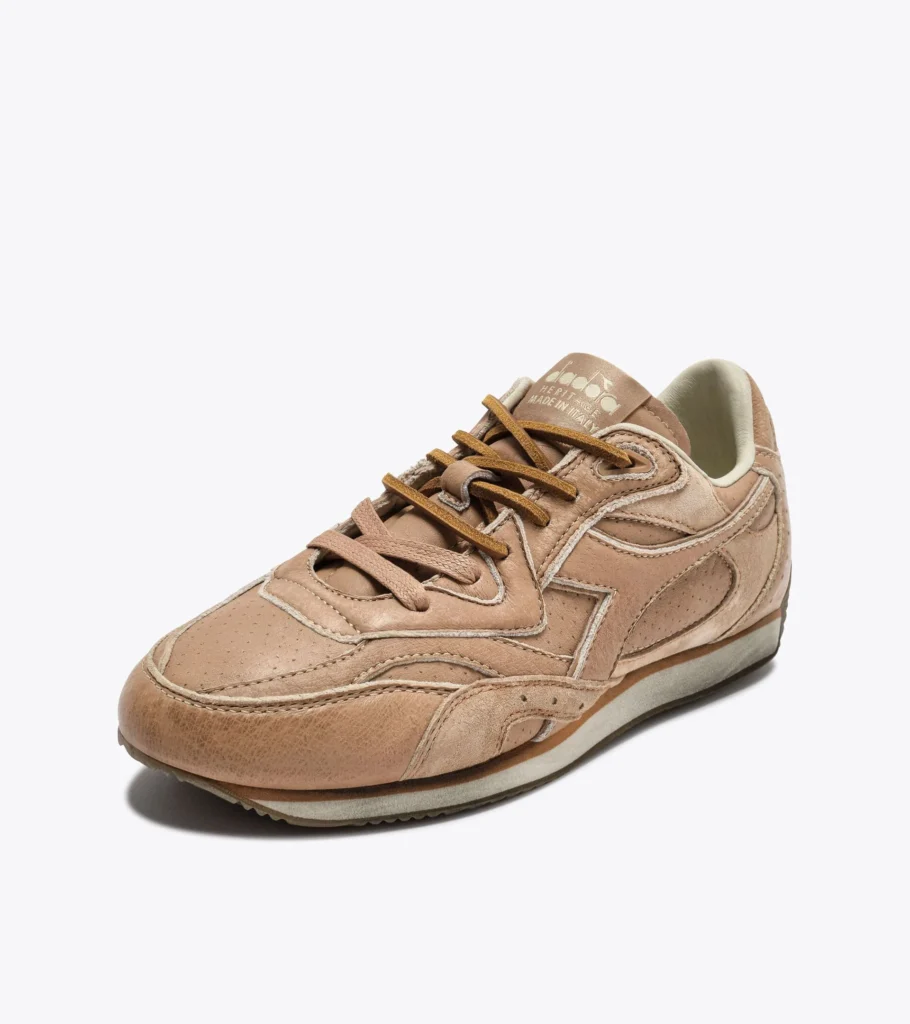 Angled view of the Diadora Equipe Revenge Dune Used Italia sneaker showing stonewashed dune full-grain leather, suede laces, perforated toe box, and “Diadora Heritage Made in Italy” tongue branding